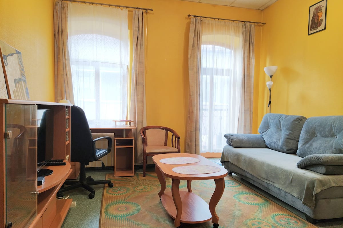 A room with a desk, chair, sofa, and a small table.