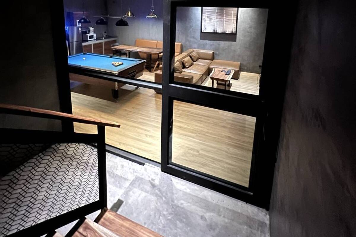 A modern interior with a pool table, leather sofa, and wooden flooring.