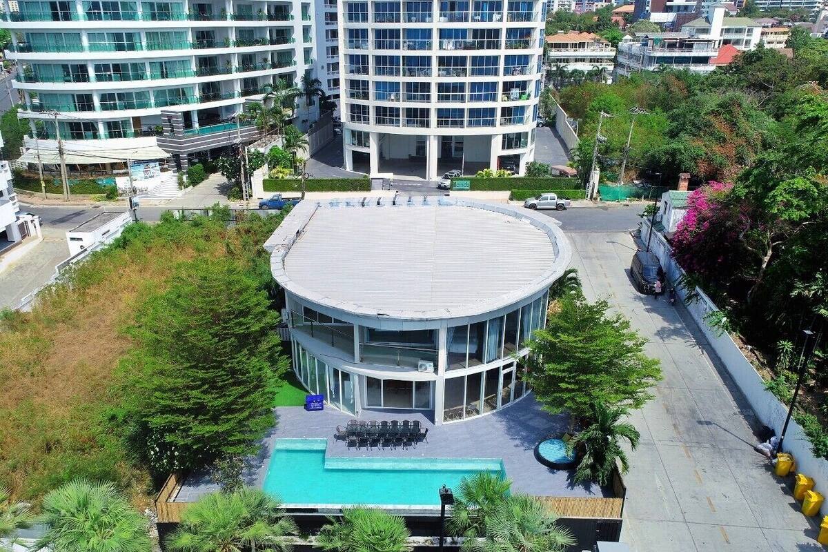 A modern building with a circular central courtyard, outdoor seating, and a swimming pool.