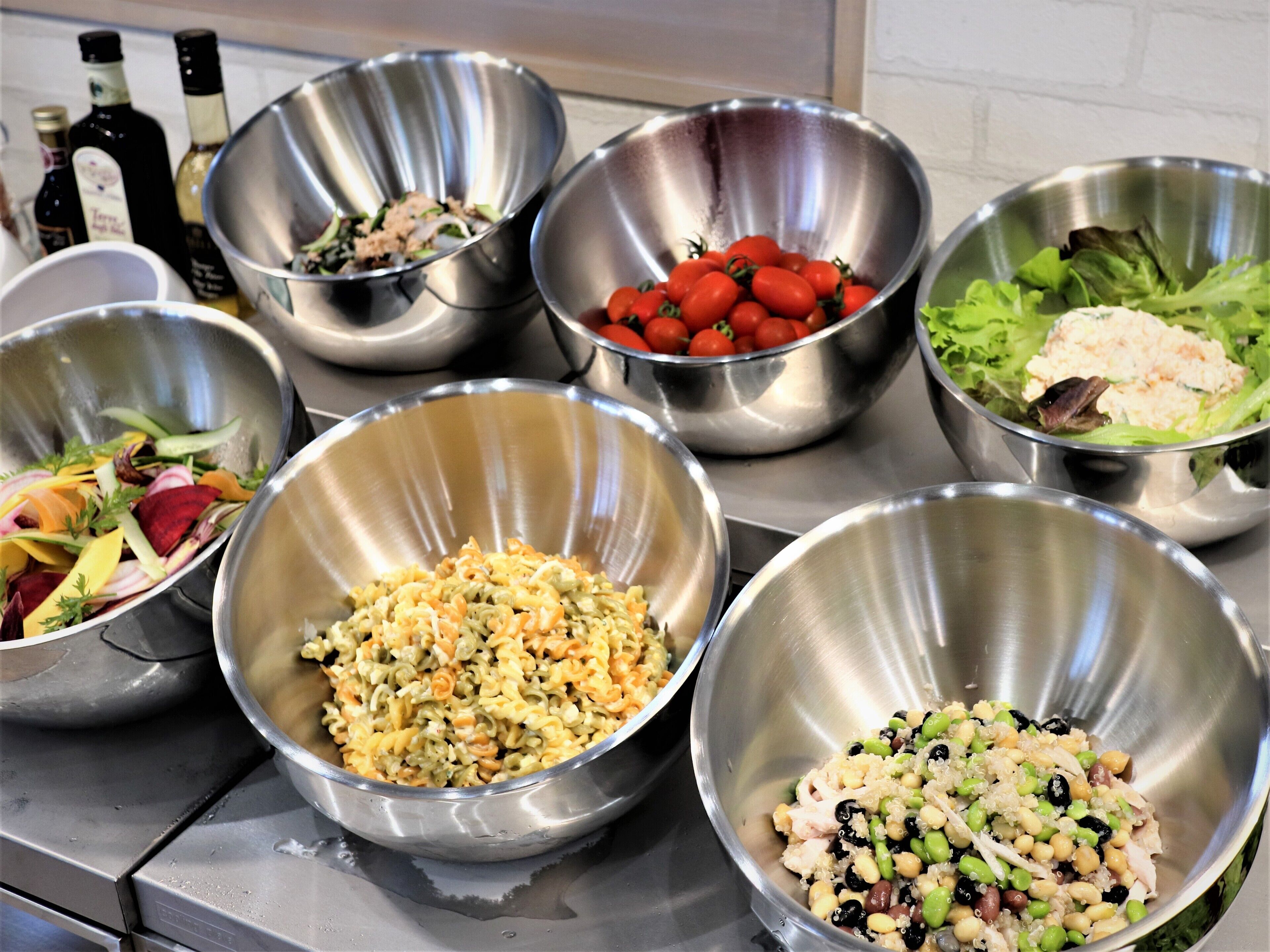 A kitchen counter with various metal bowls containing different food items.
