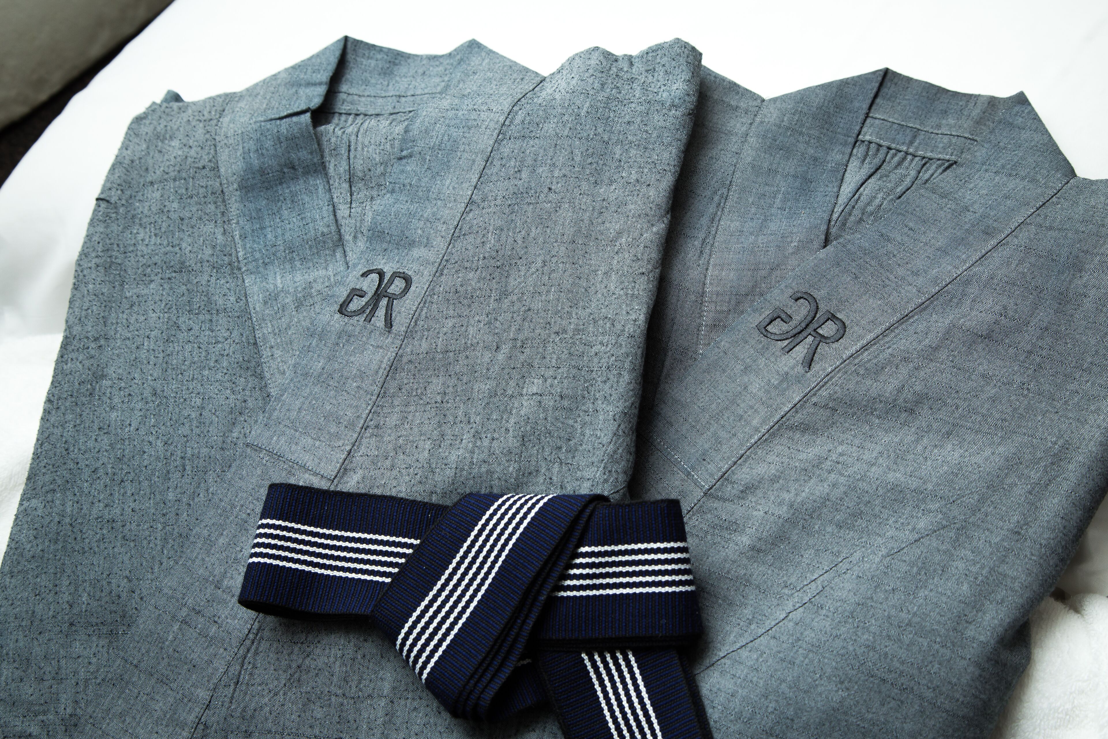A pair of grey trousers with a dark blue striped tie.