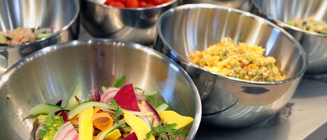 Une table de buffet avec différents plats présentés dans des bols en métal.