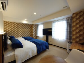 Ein Hotelzimmer mit Bett, Fernseher, Schreibtisch und Stuhl.