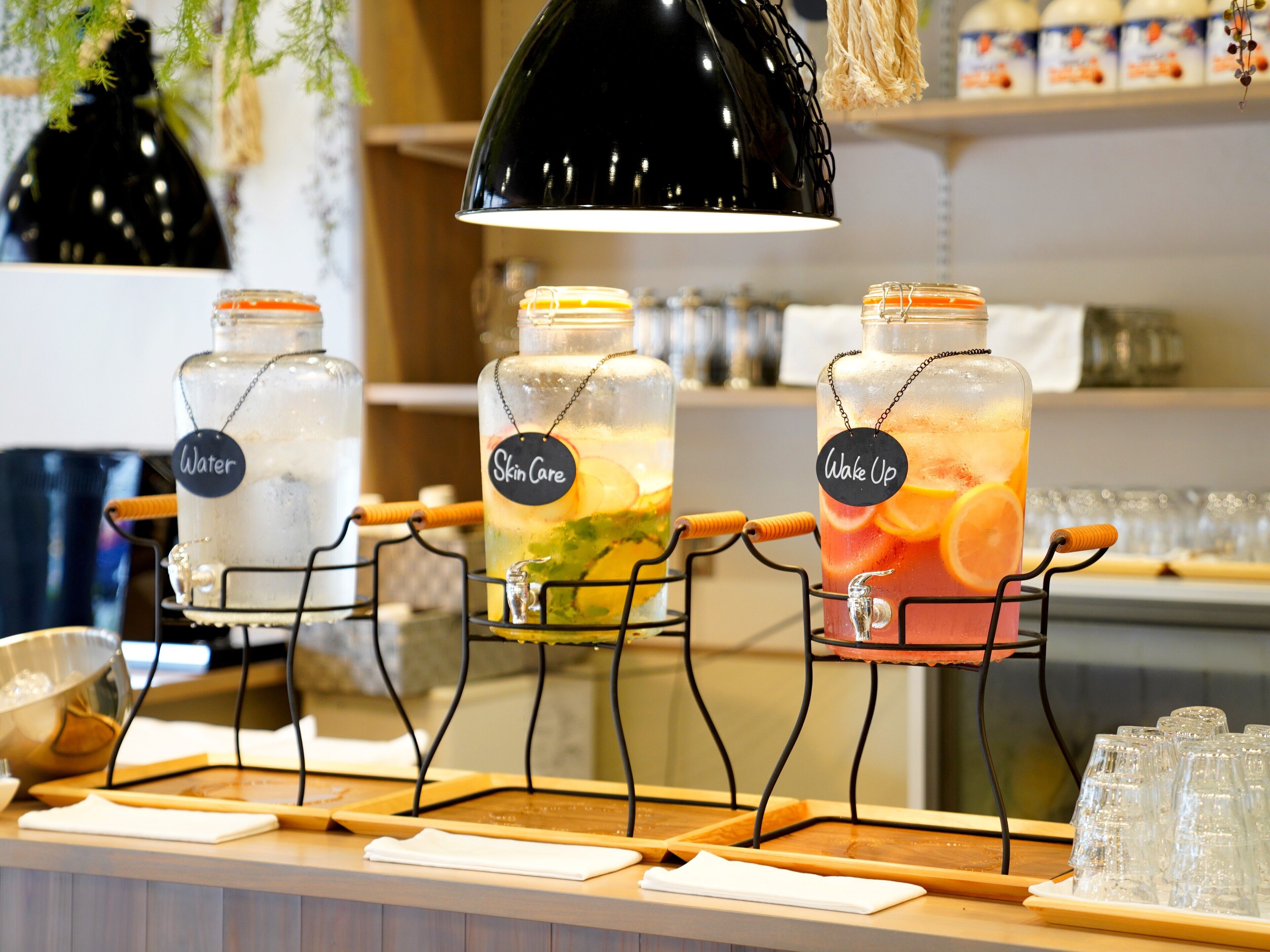 Una estación de bebidas con tres dispensadores etiquetados: Agua, Cuidado de la piel y Despertar.