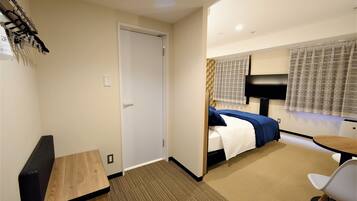 Una habitación de hotel con una cama, un escritorio, una silla y un televisor.