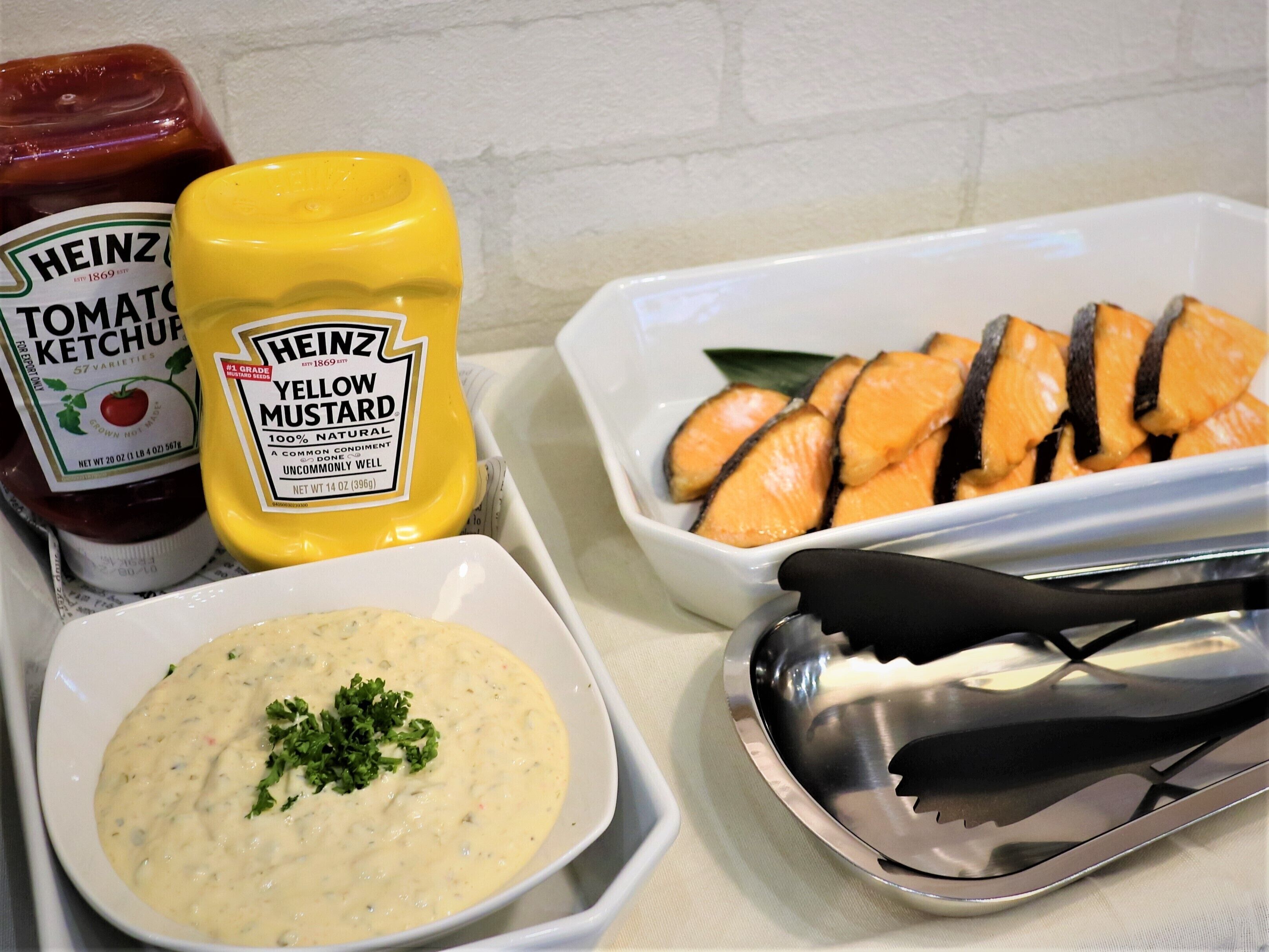 Une table avec des condiments, un bol de sauce et un plat de saumon.