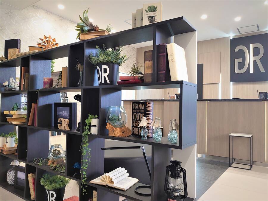 Un interior moderno con una estantería negra que muestra libros, objetos decorativos y plantas.