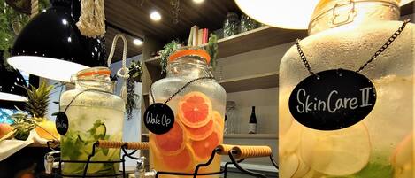 A display of large glass jars labeled "SkinCare II" with various fruits and herbs inside, arranged on a metal rack in a store.