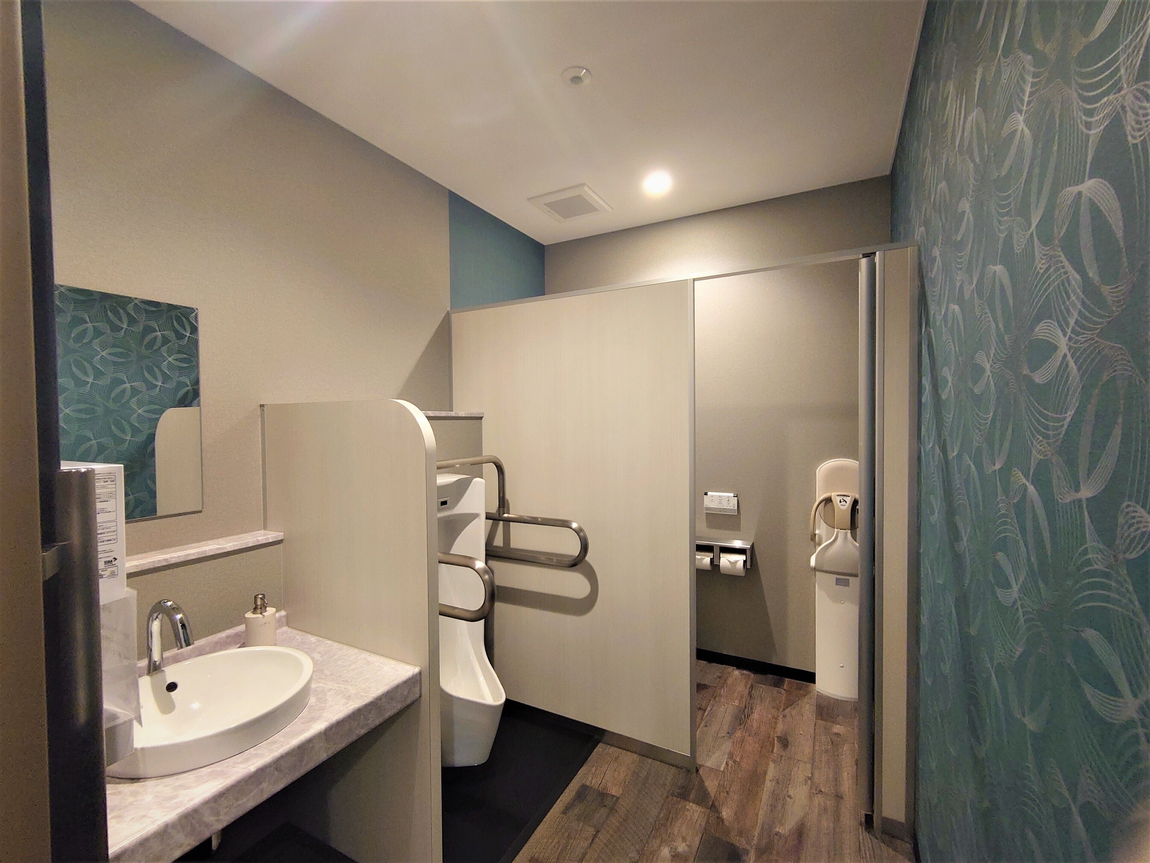 A modern bathroom with a sink, mirror, and urinal.