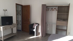 Une chambre à coucher avec un lit, un téléviseur posé sur une commode, une armoire et une chaise.
