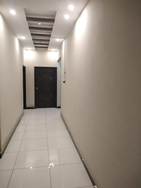 A corridor with a tiled floor and a door at the end.