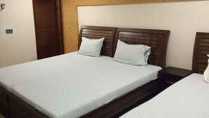 Ein Hotelzimmer mit zwei Betten, einem Holzkopfende, einer Wand mit Muster und einer Tür.