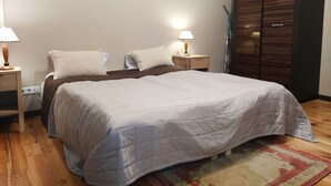 Een slaapkamer met een groot bed, twee nachtkastjes met lampen, een kledingkast en een schilderij aan de muur.