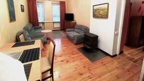 Een woonkamer met een bank, een klein rond tafeltje, een televisie en een open haard.