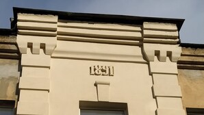 Een gevel met een groot raam en het getal '1891' erboven.