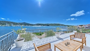 Une terrasse avec vue sur un lac, des meubles en bois et des plantes en pot.