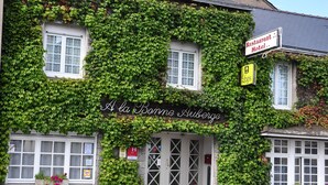 Un edificio con paredes cubiertas de hiedra, un letrero que dice "Restaurant Hotel" y un letrero de "Logis".