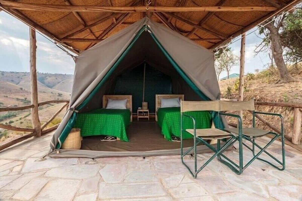 Alojamento em tenda com duas camas, uma mesinha e uma cadeira.