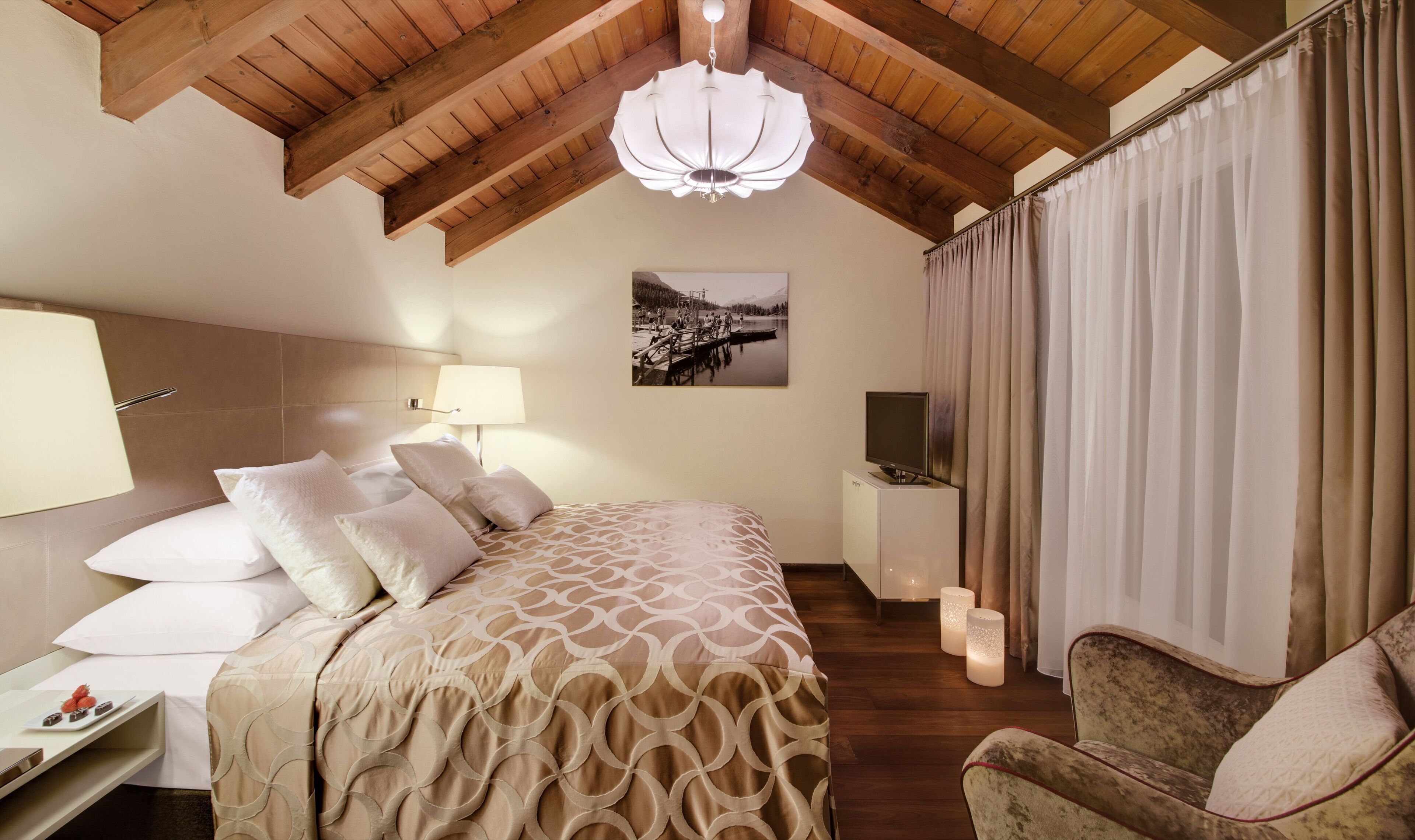 Una camera d'albergo con un letto, una scrivania, una sedia, una televisione e un quadro appeso al muro.