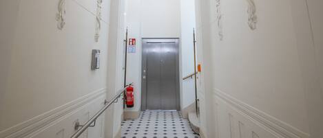 En hall med ett klinkergolv, ett ledstång och en dörr längst ner.