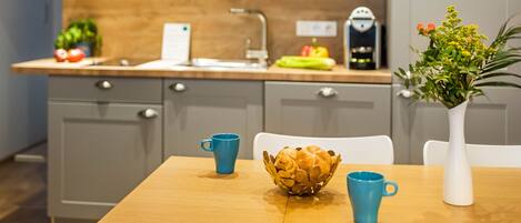 A modern kitchen with grey cabinets, a wooden countertop, and a dining table with chairs.