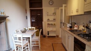A compact kitchen with a dining table, chairs, a clock, and a stove. - Kibilù - Piazzale Ghirlandaio (Milan)