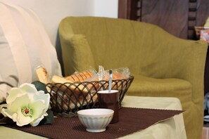 A dining area with a wicker basket containing bread and a cup, a white bowl, and a white flower on a table.