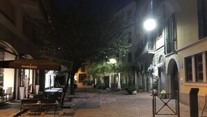 A cobblestone street at night with outdoor seating and potted plants. - Kibilù - Antica Corte Donizzetti (Varese)
