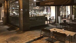 An outdoor seating area with tables and chairs, a gelato shop with a glass facade, and a sign reading "cioccolata taliani". - Kibilù - Antica Corte Donizzetti (Varese)