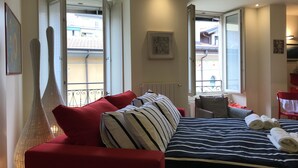 A hotel room with a bed, a red sofa, a large window, and a view of the outside. - Kibilù - Antica Corte Donizzetti (Varese)