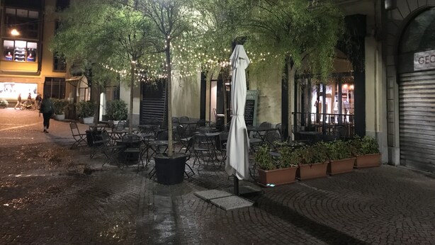 An outdoor cafe area with tables and chairs, surrounded by potted plants and a street lamp. - Kibilù - Antica Corte Donizzetti (Varese)