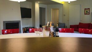 A modern living room with a round table, red chairs, a flat-screen TV, a fireplace, and a red sofa. - Kibilù - Antica Corte Donizzetti (Varese)