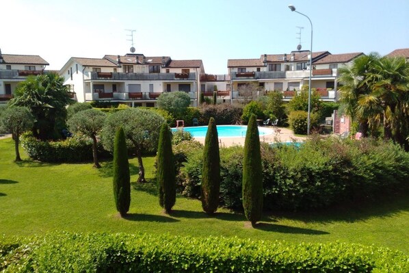 A residential complex with multiple apartment buildings, a swimming pool, and well-maintained gardens.