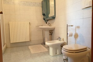 A bathroom with a toilet, bidet, sink, and towel rack.