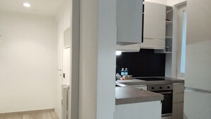 Moderni keittiö, jossa on valkoiset kaapit, musta työtaso ja ruostumattomasta teräksestä valmistetut kodinkoneet.