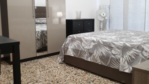 A bedroom with a bed, a wardrobe, a bedside table, and a floor lamp. - Kibilù - Via Console Marcello (Milan)