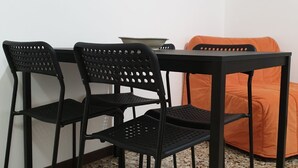 A room with a black metal table and chairs, an orange couch, and a framed world map on the wall. - Kibilù - Via Console Marcello (Milan)