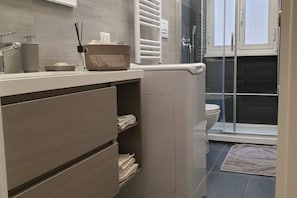 A modern bathroom with a built-in toilet, a shower area, and a towel rack.
