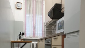 A compact kitchen with a microwave, oven, and a clock on the wall. - Kibilù - Via Console Marcello (Milan)