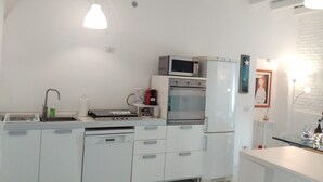 Uma cozinha compacta com armários brancos, micro-ondas, forno e máquina de café.