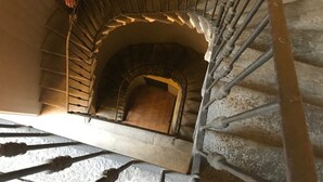 Uma escadaria em espiral com um arco de pedra que dá acesso a um andar inferior.