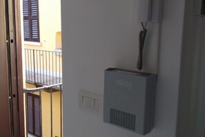 A room with a white wall, a window with brown shutters, a door, and a wall-mounted air conditioning unit labeled 'Vikey'. - Kibilù - Via Marghera (Milan)