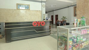 Ein Empfangstresen mit einem 'OYO'-Schild, einer Uhr und einer Theke mit verschiedenen Gegenständen.