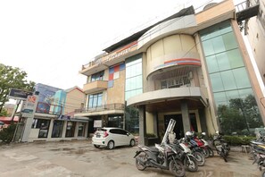 A hotel with a modern facade, a car parked in front, and several motorcycles parked outside.