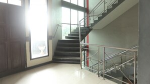 Eine Treppe mit Metallgeländern, einer Holztür und großen Fenstern, die viel natürliches Licht hereinlassen.