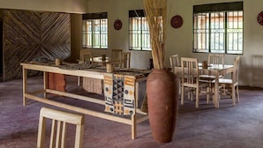 A room with a central table, chairs, a large vase, and patterned walls. - Gorilla Valley Lodge (Bwindi)
