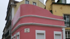 A pink building with a sign reading "Largo de Jesus" and a cobblestone street.