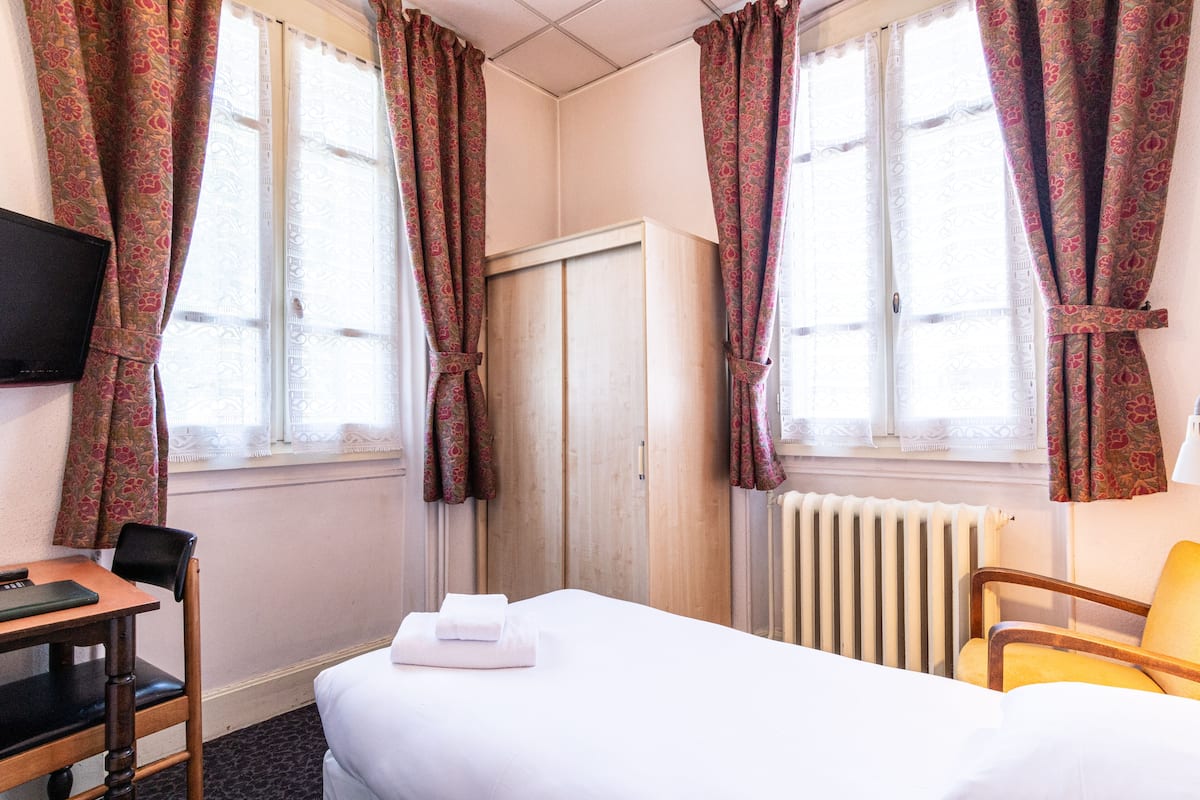 Een hotelkamer met een bed, een bureau, een stoel en een televisie aan de muur.