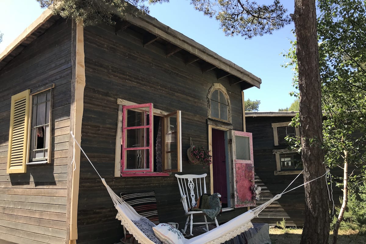 Ein rustikales Holzhaus mit Veranda, einer Hängematte und einem kleinen Stuhl.