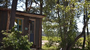 Eine rustikale Holzhütte mit Veranda und einem Fenster mit Vorhängen.